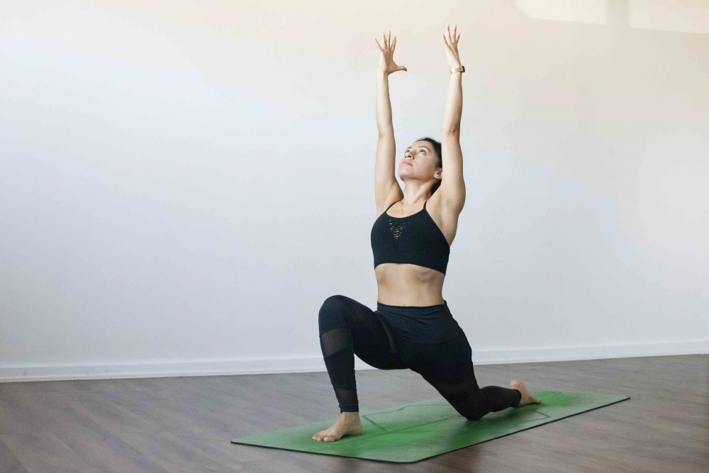 Low lunge pose  with Female yogi on green yoga mat